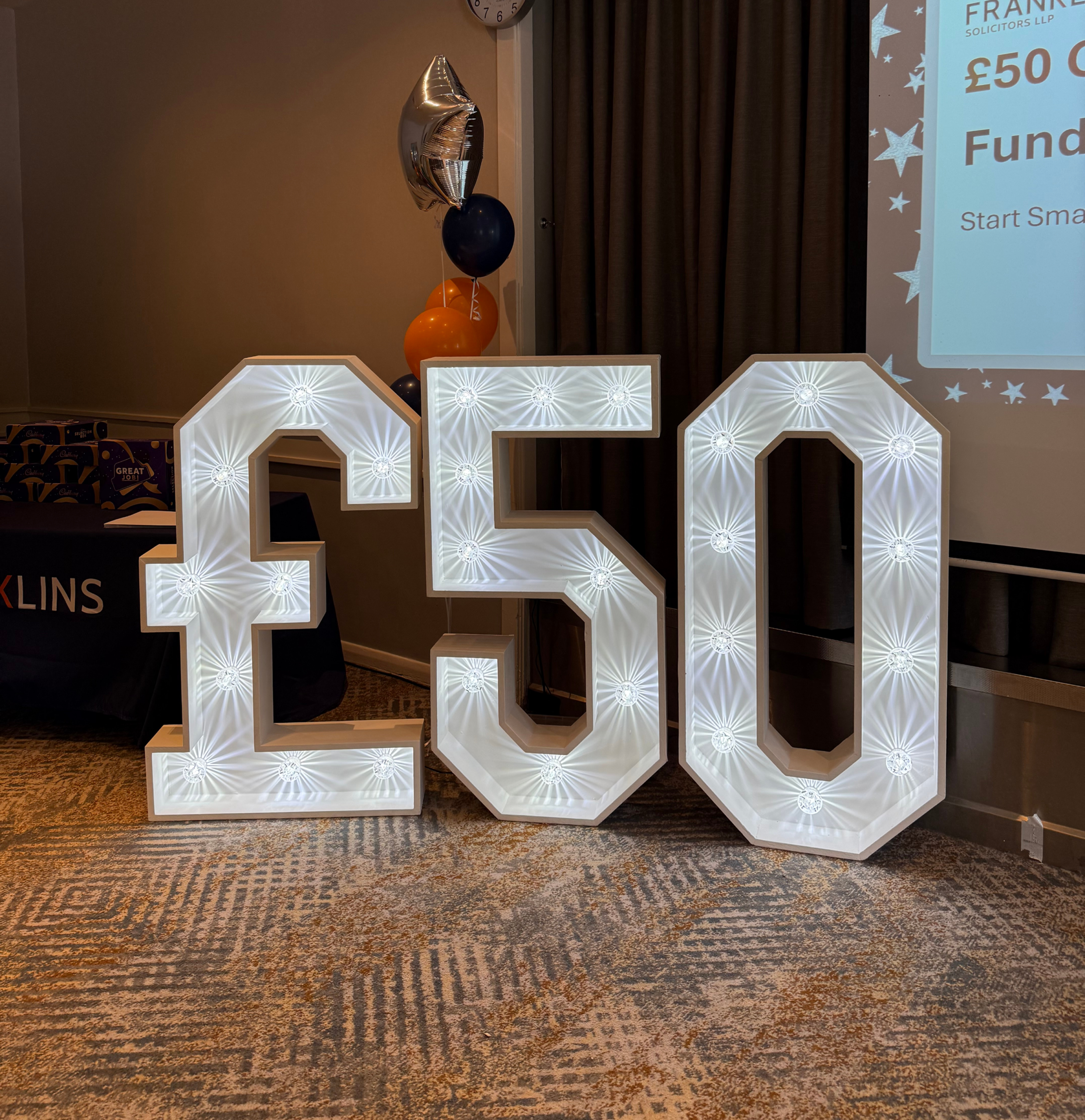 Illuminated £50 display with balloons at a Franklins £50 Challenge fundraising event.