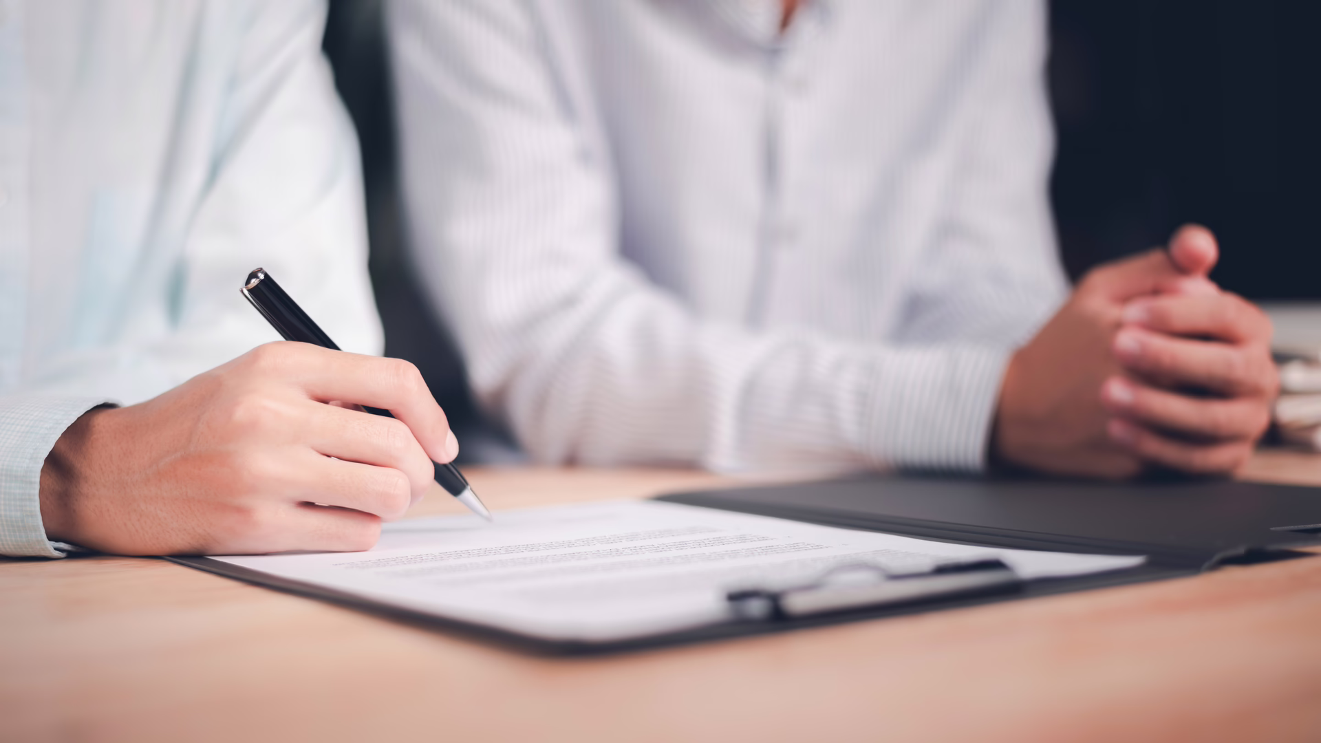 Individual signing and reviewing a formal agreement at a table.
