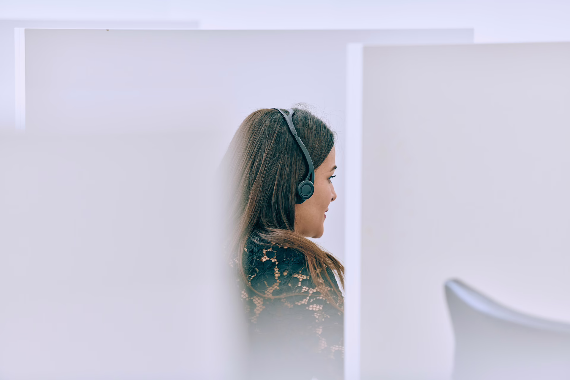 Professional wearing headphones in a quiet partitioned workspace