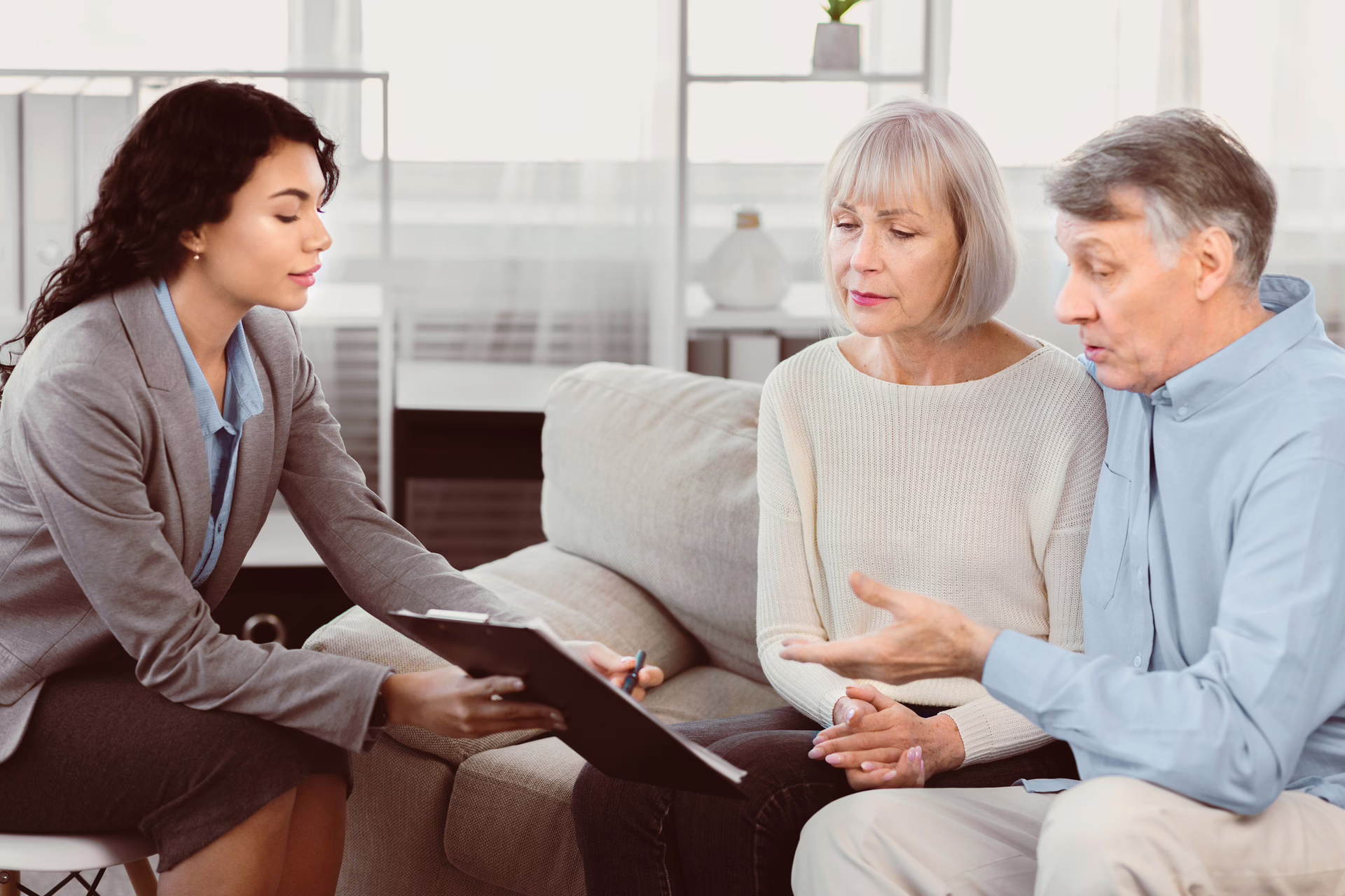 Solicitor meeting with a mature couple on a sofa reviewing documents together.