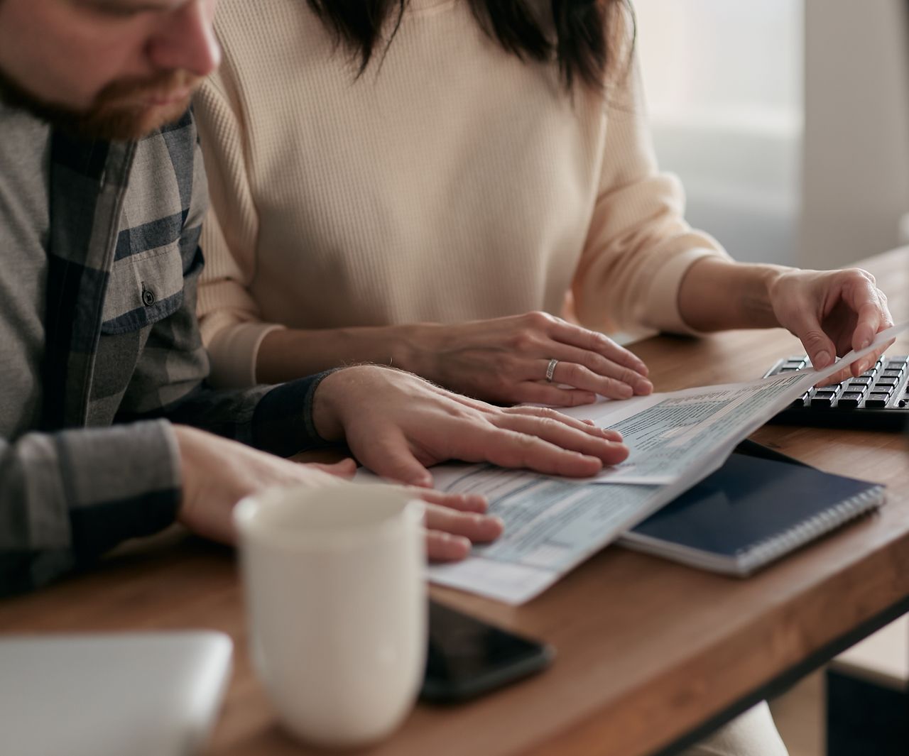 A couple reviewing legal documents together at their home office desk, planning their financial protection and will